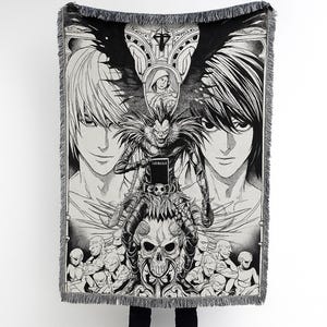 May include: Black and white woven throw blanket featuring a detailed illustration of anime characters. The design includes a central figure with a skull, surrounded by other characters and the text "LELUA". The blanket has a fringed edge.