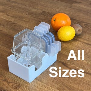 Peut inclure: Un organisateur en plastique bleu clair contenant des récipients de conservation alimentaires en verre transparent avec des couvercles bleus. Une orange, un citron jaune et un kiwi sont à côté de l'organisateur. Le texte "All Sizes" est en blanc.