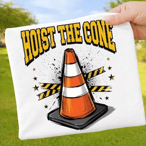 Puede incluir: Camiseta blanca con un gr&aacute;fico de un cono de tr&aacute;fico naranja y blanco. El texto "HOIST THE CONE" es amarillo. El dise&ntilde;o incluye salpicaduras negras, estrellas amarillas y cinta de precauci&oacute;n.