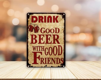 May include: A rectangular metal sign with a distressed, vintage look. The sign features the words "DRINK GOOD BEER WITH GOOD FRIENDS" in red lettering. Two beer mugs are depicted above the word "BEER".