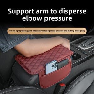 Può includere: Un bracciolo per auto bordeaux con un motivo trapuntato e una tasca. Il bracciolo ha un telefono e un portafoglio nella tasca. Il testo sull'immagine recita "Support arm to disperse elbow pressure".