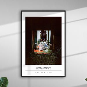 May include: Framed art print featuring a group of people in a dimly lit room. The print has the word "WEDNESDAY" and "RAT SAW GOD" printed at the bottom. The artwork is framed in a black frame and is hanging on a white wall.