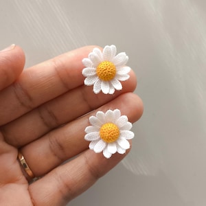 Peut inclure: Deux appliqués de fleurs de marguerite faits à la main. Chaque appliqué présente des pétales blancs entourant un centre jaune vif. Ces petites décorations florales délicates sont idéales pour l'artisanat et ajoutent une touche de nature.