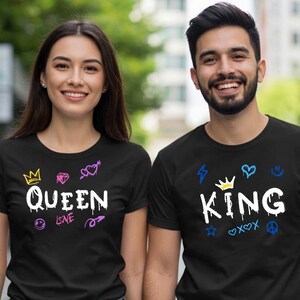 Puede incluir: Dos personas con camisetas negras a juego con texto blanco y diseños coloridos estilo grafiti. Una camiseta dice "QUEEN" con una corona y otros símbolos. La otra dice "KING" con una corona y otros símbolos. Ambos llevan vaqueros azules.