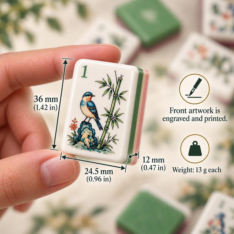 Pode incluir: Uma pe&ccedil;a de Mahjong branca com o n&uacute;mero 1 em verde, um p&aacute;ssaro azul e laranja sobre uma rocha e caules de bambu verdes. A pe&ccedil;a mede 36 mm de altura, 24,5 mm de largura e 12 mm de profundidade, com um peso de 13 g.
