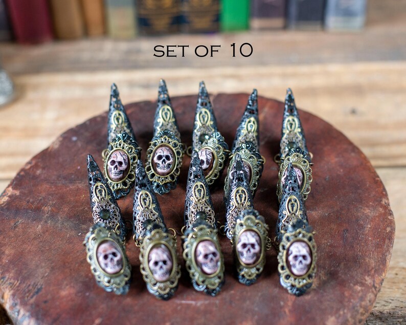 Set of 10 gothic claw rings with skulls displayed on rustic background.