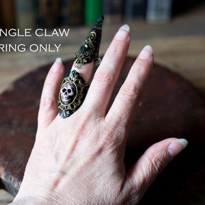 Single claw ring worn on one finger showing adjustable design.