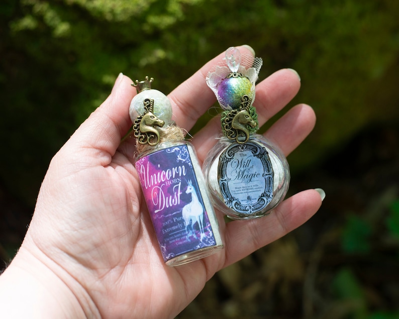 Puede incluir: Dos peque&ntilde;as botellas de vidrio con tapones de corcho y tapas decorativas de metal en forma de unicornio. Las botellas est&aacute;n llenas de polvo blanco y tienen etiquetas que dicen "Unicorn Horn Dust" y "The Will & Magic".