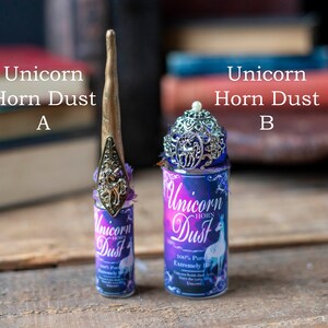 Puede incluir: Dos frascos peque&ntilde;os de polvo de cuerno de unicornio, uno con un adorno de unicornio plateado y el otro con un adorno de cuerno de unicornio plateado. Ambos frascos tienen una etiqueta morada y azul con el texto "Polvo de cuerno de unicornio" y "100% Puro Extremadamente Raro".