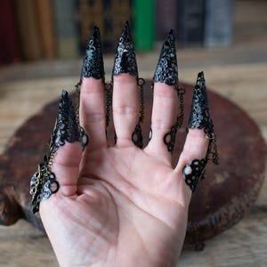 Back view showing adjustable ring bands and chain details on nail claws.