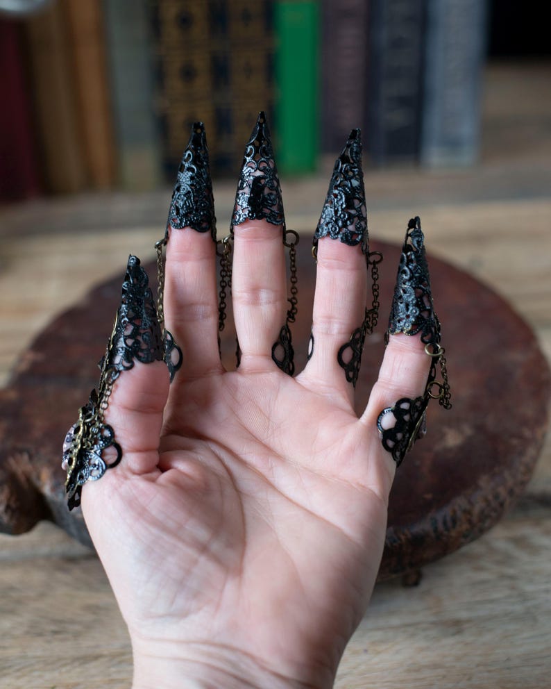 Back view showing adjustable ring bands and chain details on nail claws.