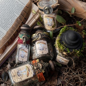 May include: An assortment of apothecary jars with decorative lids and labels reading "Deadly Death Cap". The jars are filled with dried herbs and are adorned with vintage-style embellishments. A black hat is covered in moss. A book and feather are in the background.
