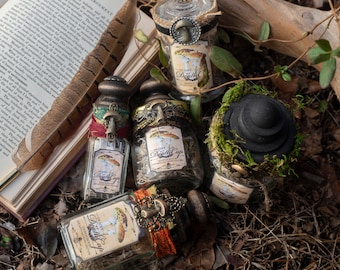 May include: An assortment of apothecary jars with decorative lids and labels reading "Deadly Death Cap". The jars are filled with dried herbs and are adorned with vintage-style embellishments. A black hat is covered in moss. A book and feather are in the background.