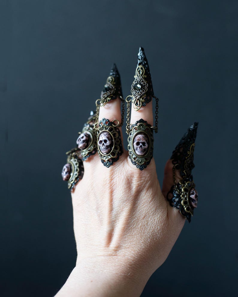 Full hand wearing 5 of the 10-piece gothic mermaid nail claws with resin skulls and filigree details.