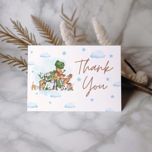 May include: A white card with a watercolor illustration of cartoon characters and the words "Thank You" in a brown script font. Blue stars and clouds decorate the background.