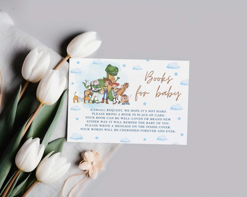 May include: A baby shower invitation card with the text "Books for baby" in gold script. The card features illustrations of characters from the Toy Story movie, with a blue watercolor background and white clouds.