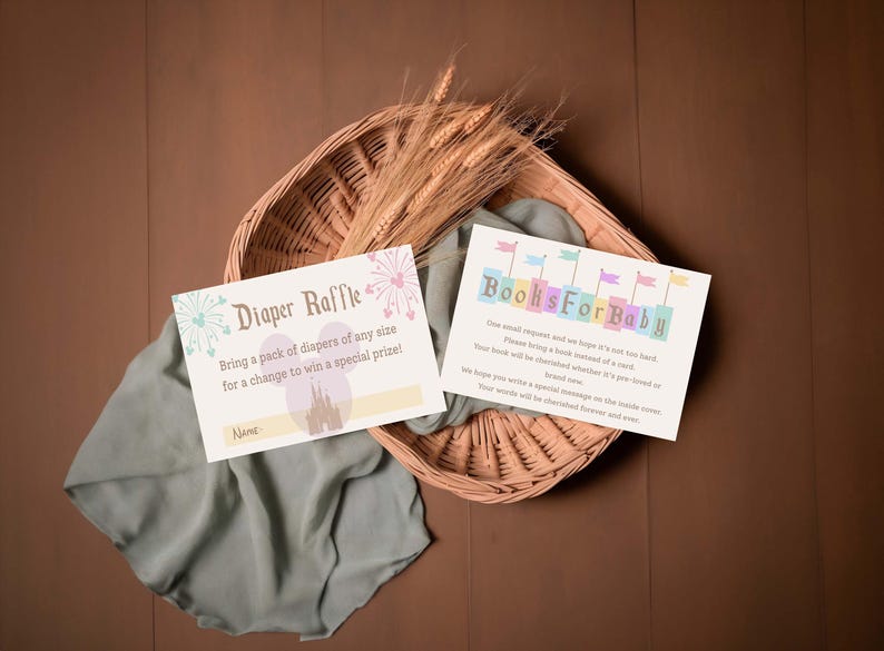 May include: Two baby shower invitation cards with text, "Diaper Raffle" and "Books For Baby", rest on a woven basket with wheat stalks. The cards have pastel colors and whimsical designs, perfect for a baby shower.