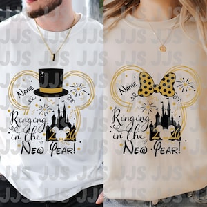 Op de afbeelding: Twee witte en beige crewneck shirts met een Nieuwjaarsontwerp. Het ontwerp bevat een hoge hoed en strik, vuurwerk, een kasteel en de tekst "Ringing in the New Year!" met ruimte voor een naam.