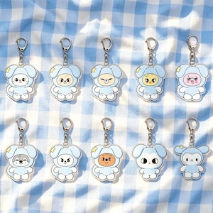 May include: Ten acrylic keychains featuring cartoon characters wearing light blue animal-themed hoods with floppy ears. Each character has a unique facial expression and is attached to a silver-toned metal lobster clasp and a small chain link.
