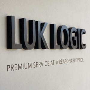 Puede incluir: Un letrero tridimensional que presenta el texto negro, en negrita y sin remates LUK LOGIC montado en una pared de color claro. Debajo de las letras principales, el texto PREMIUM SERVICE AT A REASONABLE PRICE está impreso en una fuente oscura.