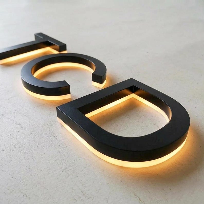Puede incluir: Letras tridimensionales T, C y D con acabado en negro mate. Cada letra cuenta con una tira de luz LED blanca c&aacute;lida integrada a lo largo del borde inferior, creando un efecto brillante que ilumina la superficie bajo los caracteres.