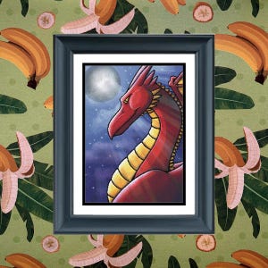 May include: A framed art print featuring a red dragon with yellow underbelly scales against a dark blue night sky with a full moon and stars. The artwork is enclosed in a black rectangular frame with a white mat border, centered on a background.