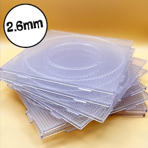 May include: A stack of clear plastic pegboards, each with a grid of small holes for crafting. The boards are transparent, allowing a view through the stack. The text "2.6mm" is in a white circle in the upper left corner.