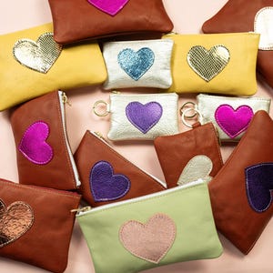 Cartera Be Still My Heart Mae. Cartera de piel en dorado claro. Cartera de piel en color champán metalizado. Cartera de piel con forma de corazón en piel en color platino imagen 5