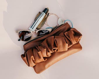 Clutch pequeño tipo sobre. Bolso clutch espacioso de piel color caramelo. Clutch de piel color camel con correa. Clutch con asa para la mano