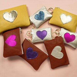 Cartera Be Still My Heart Mae. Cartera de piel en dorado claro. Cartera de piel en color champán metalizado. Cartera de piel con forma de corazón en piel en color platino imagen 4