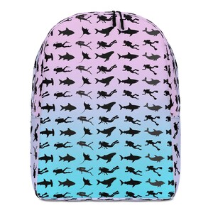 May include: A backpack featuring a gradient background transitioning from light pink at the top to light blue at the bottom. The surface is covered in a repeating black silhouette pattern of scuba divers, sharks, whales, dolphins, and manta rays.