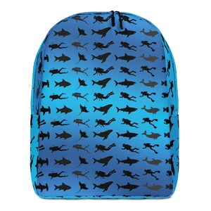 Könnte beinhalten: Ein blauer Rucksack mit einem sich wiederholenden Muster aus schwarzen Silhouetten von Tauchern, Haien, Rochen und Delfinen. Die Tasche hat einen Farbverlauf, der von einem helleren Blau oben zu einem dunkleren Blau unten übergeht.