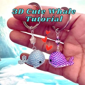 May include: Two beaded whale keychains, one light blue and one purple, are displayed. The keychains are attached to silver rings. The image includes the text "3D Cute Whale Tutorial" in a turquoise font. Red heart graphics are also present.