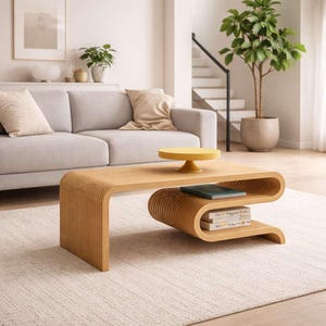 以下が含まれることがあります： ユニークな曲線デザインの、明るい木材で作られたモダンなコーヒーテーブル。テーブルには下の棚と黄色の円形トレイがあります。グレーのソファと鉢植えの植物があるリビングルームにあります。