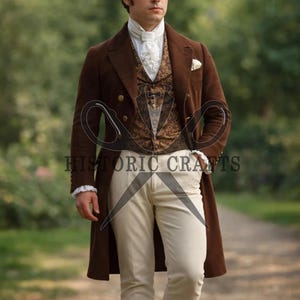 Op de afbeelding: Een bruine dubbelbreasted jas met gouden knopen, gedragen over een patroonvest en een wit overhemd met een gefranjerde kraag. De outfit bevat crèmekleurige broeken. De tekst "HISTORIC CRAFTS" is zichtbaar.