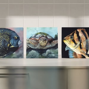 Può includere: Tre dipinti ad acquerello incorniciati di vita marina. Il primo dipinto presenta un pesce angelo bianco e nero. Il secondo dipinto presenta una tartaruga marina con un guscio verde e marrone. Il terzo dipinto presenta un pesce a strisce con strisce arancioni, marroni e bianche.