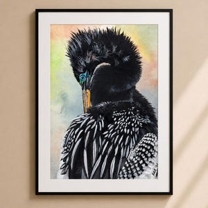 May include: A framed watercolor painting of a black bird with a long neck and a bright blue eye. The bird's feathers are detailed with white and black patterns. The background has soft watercolor washes of yellow, orange, and green.