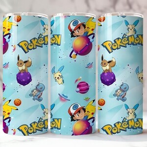 May include: Three stainless steel tumblers with a light blue background featuring various Pok&eacute;mon characters, planets, and the Pok&eacute;mon logo. The design includes Pikachu, Eevee, and Ash Ketchum. The tumblers are designed for cold beverages.