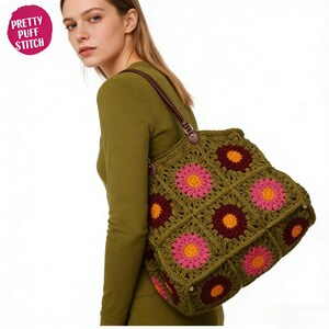 Könnte beinhalten: Eine handgefertigte, olivgrüne Häkeltasche mit einem Blumenmuster in Rosa, Orange und Burgunderrot. Die Tasche hat braune Ledergriffe und den Text "Pretty Puff Stitch" in einem rosa Kreis.