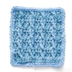 以下が含まれることがあります： テクスチャードケーブルステッチパターンが施された、正方形の明るい青色のクロシェサンプル。エッジはボーダーで丁寧に仕上げられています。糸は柔らかく見え、全体的な効果は手作りです。