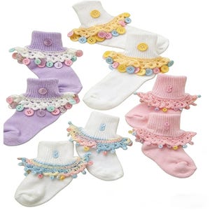May include: A collection of colorful socks with decorative lace and button details. The socks are in various pastel colors, including white, lavender, and pink. Each pair features a different color of lace and buttons.