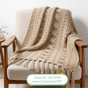 Puede incluir: Una manta de ganchillo beige con un diseño calado detallado y flecos, sobre un sillón beige con brazos de madera. La manta presenta un patrón floral repetido. El texto en la imagen dice "CROCHET PATTERN Instant Download PDF".