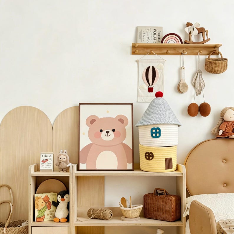 May include: A children's room scene with a framed bear illustration, a house-shaped storage basket, and a wooden shelf with decorative items. The color palette includes soft pinks, yellows, and natural wood tones, creating a cozy atmosphere.