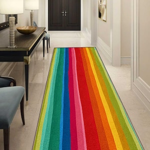 May include: A long rectangular runner rug featuring a vibrant vertical striped pattern in a rainbow of colors including lime green, emerald, teal, royal blue, magenta, bright red, orange, yellow, and chartreuse, with a thin black border.