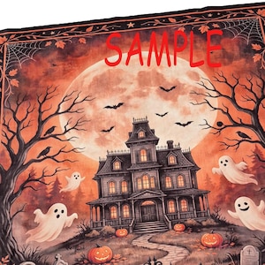 May include: A rectangular fabric tapestry featuring a Halloween scene with a large orange moon, a haunted house, flying bats, and ghosts. The word SAMPLE is printed in red across the top. Bare trees, pumpkins, and tombstones complete the design.