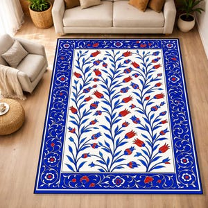 May include: A rectangular area rug with a floral design. The rug features a white background with blue stems and red and blue flowers. A blue border with floral patterns frames the rug.