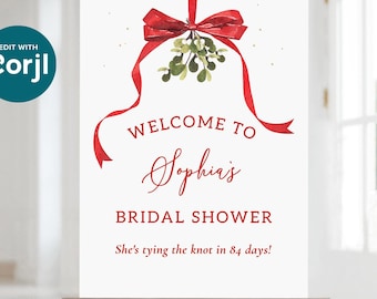 May include: A white welcome sign with red text and a red ribbon with a mistletoe design. The text reads "Welcome to Sophia's Bridal Shower She's tying the knot in 84 days!"