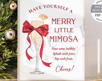 May include: A framed print with the text "Have Yourself a Merry Little Mimosa" in red. The image features a watercolor illustration of a mimosa in a champagne flute with a red bow. The print is surrounded by a green wreath and gold ornaments.