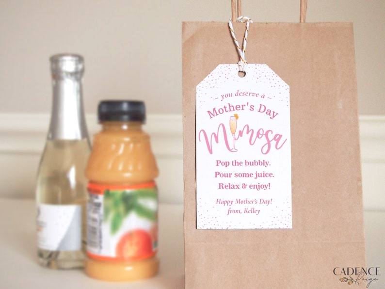 Pu&ograve; includere: Un'etichetta regalo bianca con testo rosa che dice "ti meriti un Mimosa della Festa della Mamma". L'etichetta include anche una piccola illustrazione di una bevanda mimosa e il testo "Stappa le bollicine. Versa un po' di succo. Rilassati e goditi! Buona Festa della Mamma! da Kelley".
