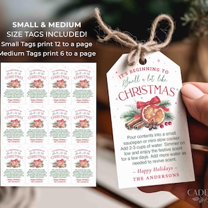 Puede incluir: Etiquetas de regalo navide&ntilde;as blancas con el texto "It's beginning to smell a lot like Christmas". Las etiquetas presentan ilustraciones de palitos de canela, rodajas de naranja y un lazo rojo. Las etiquetas peque&ntilde;as imprimen 12 por p&aacute;gina, medianas 6.